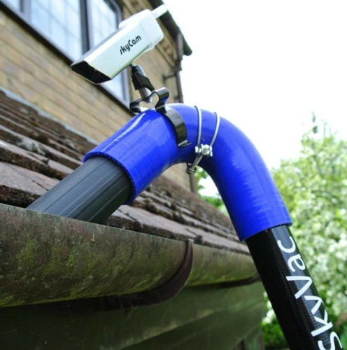 Technician cleaning gutter with safety equipment